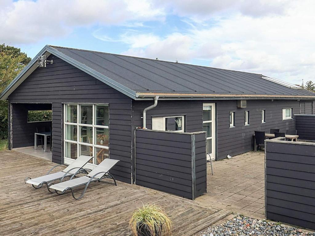 a black building with two chairs on a patio at 4 star holiday home in Karrebæksminde in Enø By