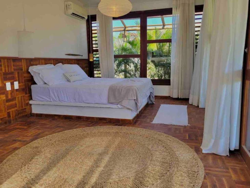 a bedroom with a bed and a large window at Chalé Koa Flora - PRAIA DE MOITAS in Amontada