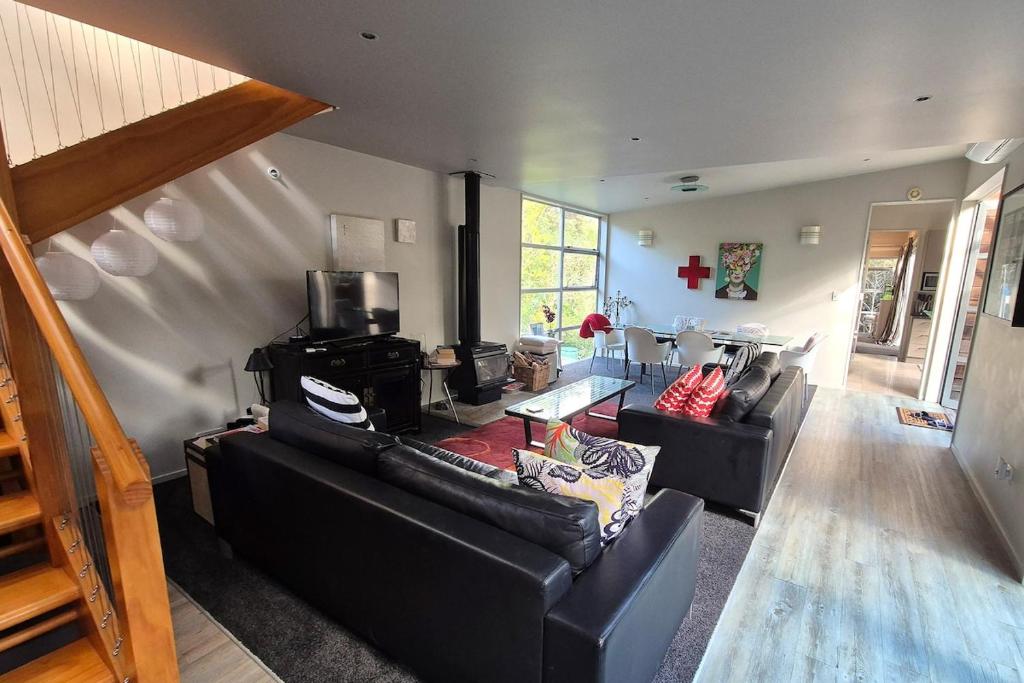 a living room with two black leather couches at beach bush retreat at Leigh in Leigh