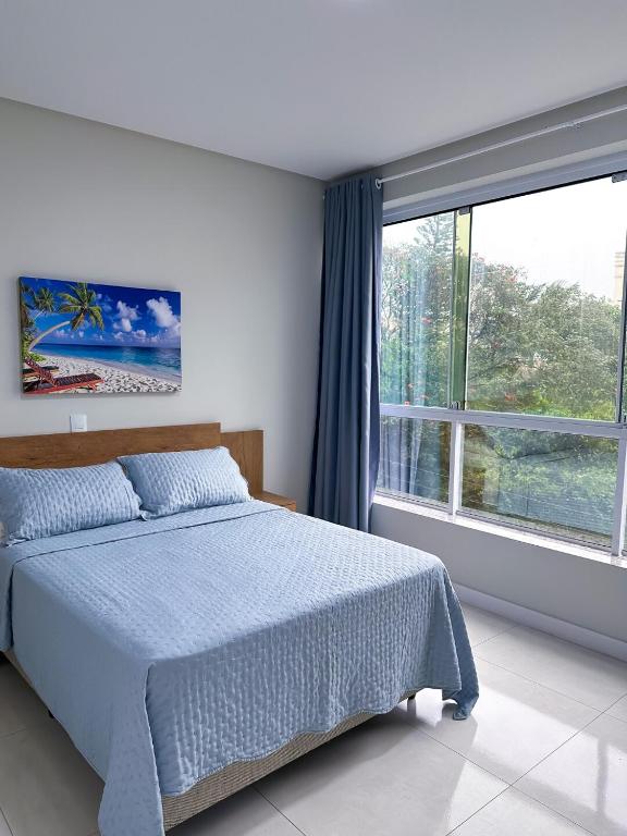 a bedroom with a bed and a large window at Residencial Spader - Bombinhas in Bombinhas