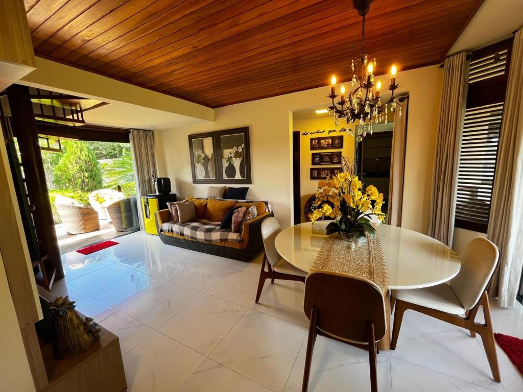 a dining room with a table and a couch at Bangalô aconchegante e luxuoso Winterville Resort Gravatá PE in Gravatá