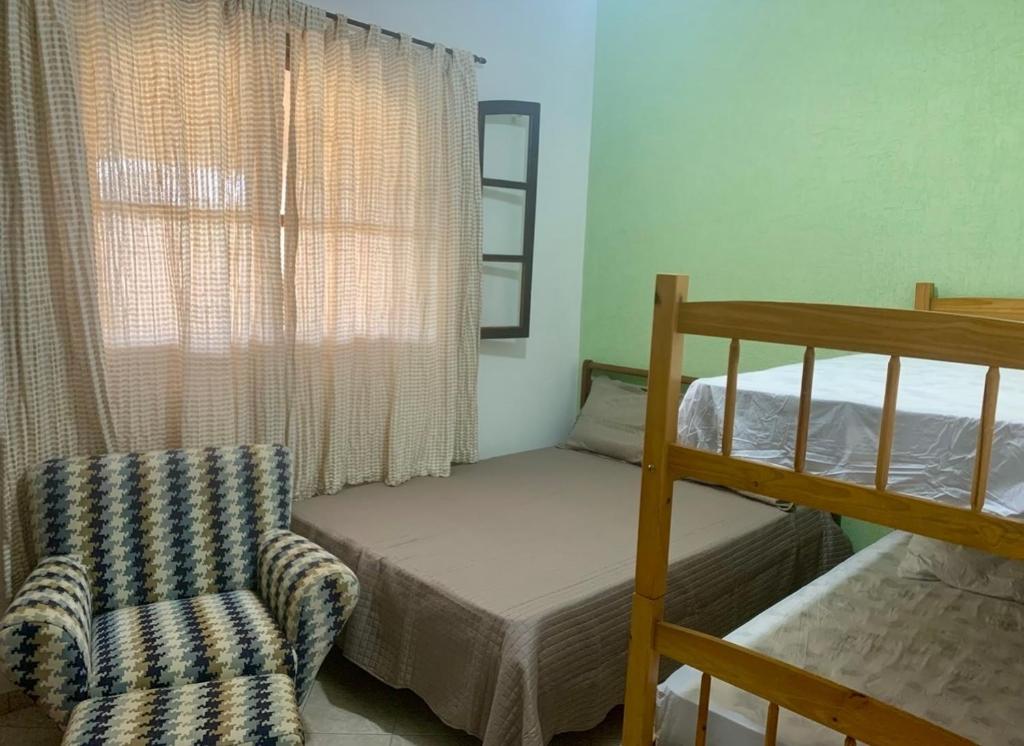 a bedroom with a bunk bed and a chair at Casa em Ilhabela - Próxima à Praia do Curral in Ilhabela
