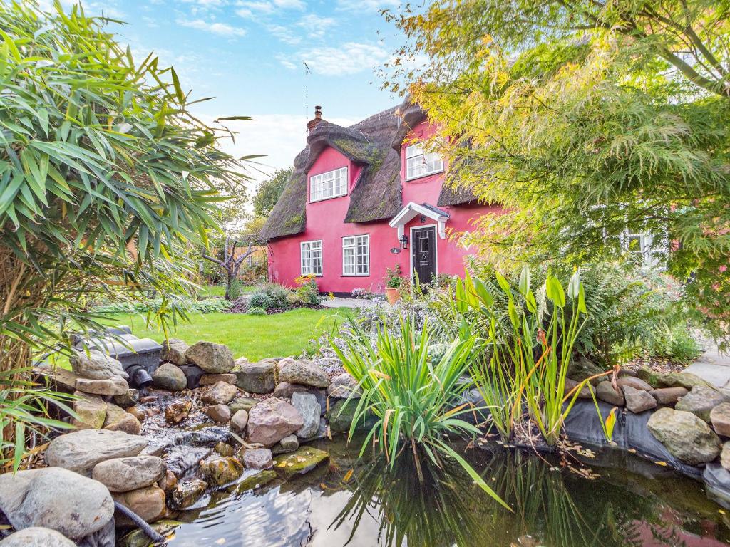 a red house with a creek in front of it at All Saints Cottage in Saffron Walden