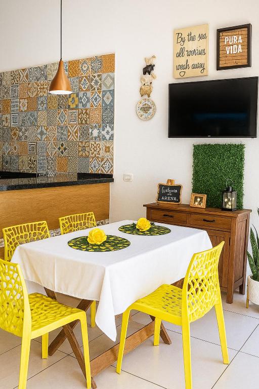 a dining room with a white table and yellow chairs at Mini Garden kitnet in Paranavaí