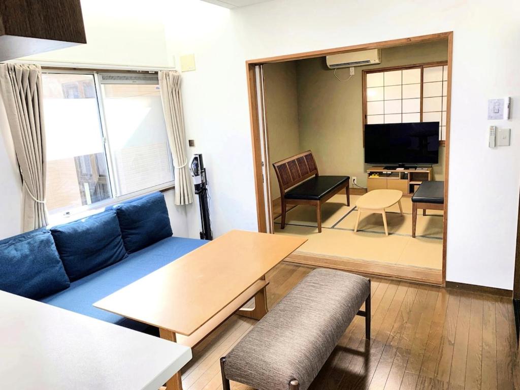 a living room with a blue couch and a table at Shibuya Ward Tokyo Private for 10 people with Piano room 貸切10名様 ピアノと防音室 新宿駅から4分の幡ヶ谷駅徒歩11分 渋谷駅直通バス停徒歩1分 in Tokyo