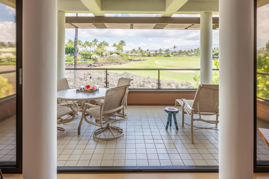balcón con mesa y sillas y vistas a un campo de golf en 1BR Mauna Lani Point lovely mountain views, en Waikoloa