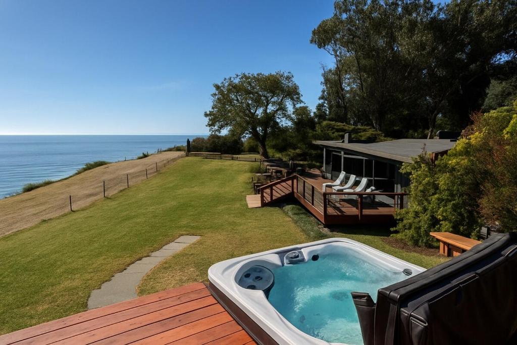 a hot tub on a deck next to a house at Spectacular Bolinas Oceanfront Retreat in Bolinas