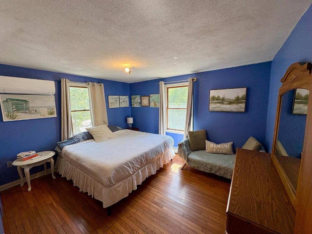a bedroom with blue walls and a bed and a chair at The Purple Room with private bath in Narragansett