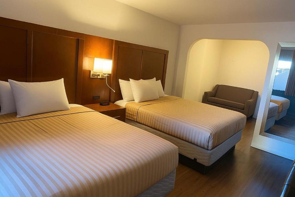 ein Hotelzimmer mit zwei Betten und einem Stuhl in der Unterkunft Valley Inn in Phoenix