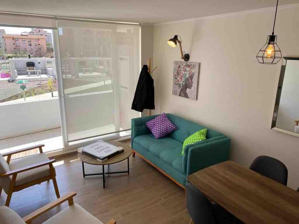 拉塞雷纳La Serena Apartment的客厅里有一张绿色的沙发和一张桌子