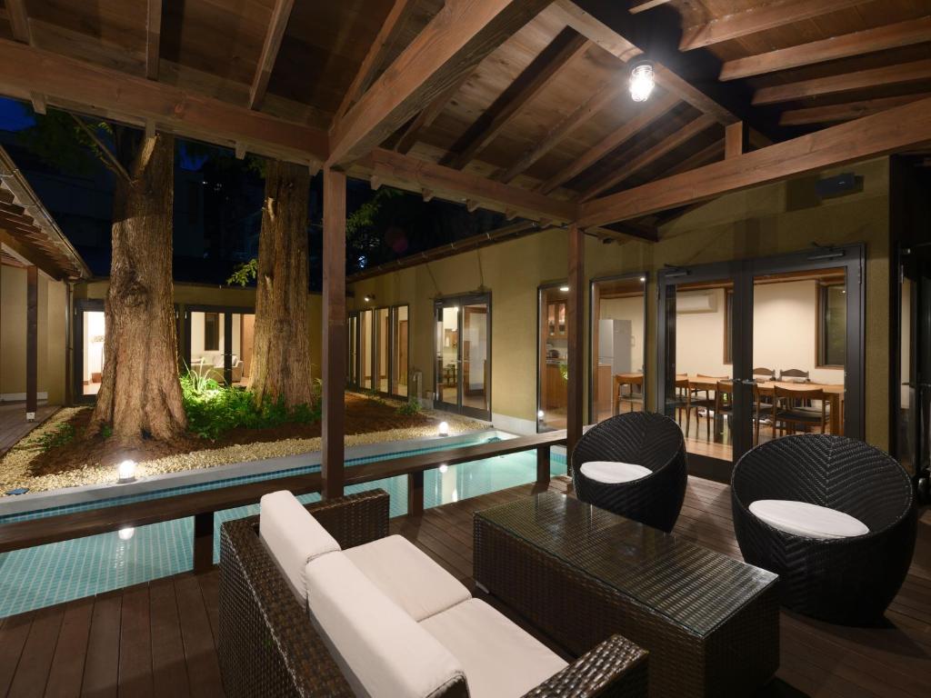 an outdoor patio with a pool and furniture and a tree at the villa NOKI in Wada