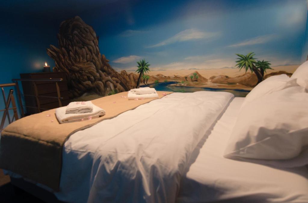 a bedroom with two beds and a painting of a beach at River Lodge Hotel Insolite in Maredsous