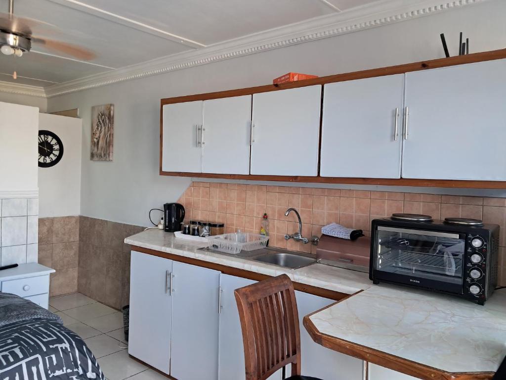 a kitchen with white cabinets and a sink and a microwave at Lion's Cave 2 in Mossel Bay