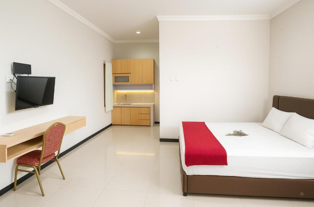 a bedroom with a bed and a desk and a television at Djuragan Kamar Dmangkoe in Bonorejo