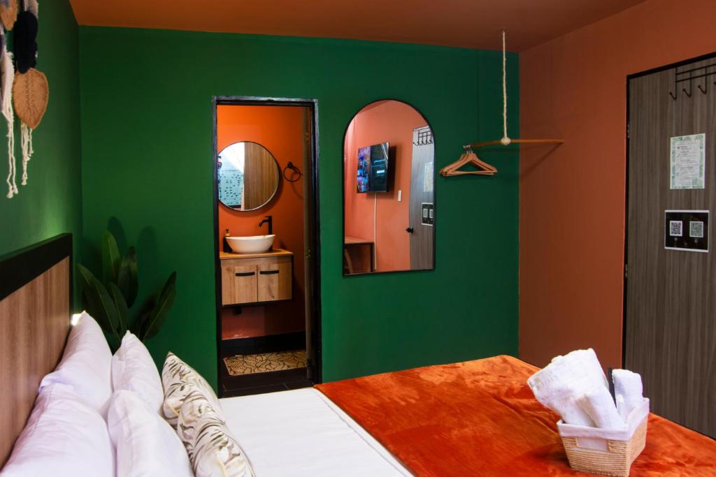 a green bedroom with a bed and a mirror at Bohemia Boutique Hostel in Cali