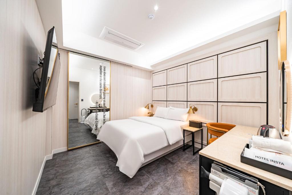 a bedroom with a white bed and a mirror at HotelInsta Main Branch in Pŏlt'ŏ