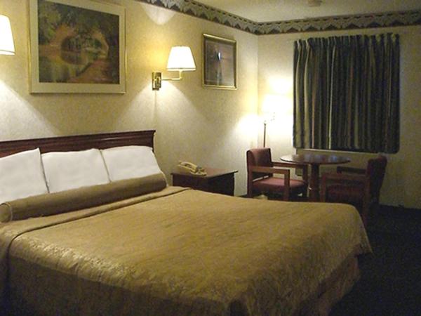 a hotel room with a large bed and a table at Red Carpet Inn Williamstown in Williamstown