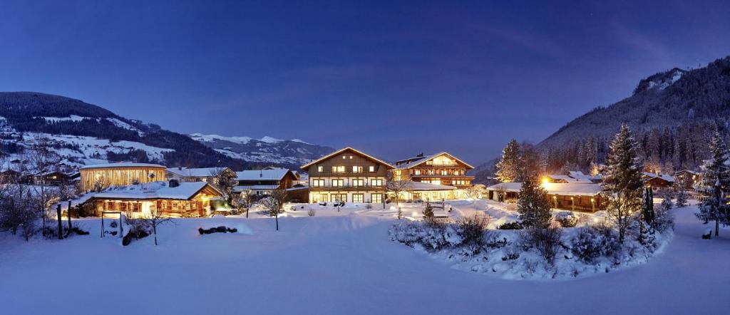 ein großes Haus im Schnee in der Nacht in der Unterkunft Wanderhotel Kirchner in Bramberg am Wildkogel