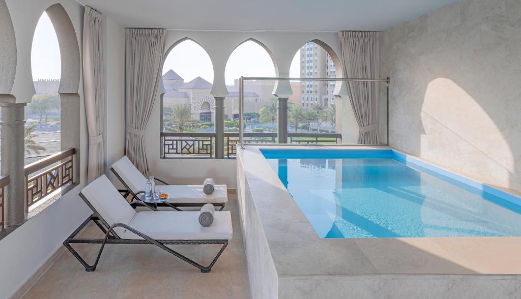 a swimming pool in a hotel room with a chair at Oaks Ibn Battuta Gate Dubai in Dubai