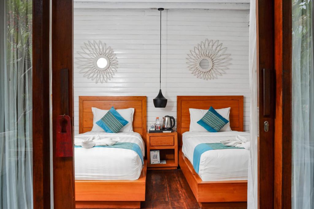a bedroom with two beds and a mirror on the wall at Sadev Resort in Gili Trawangan
