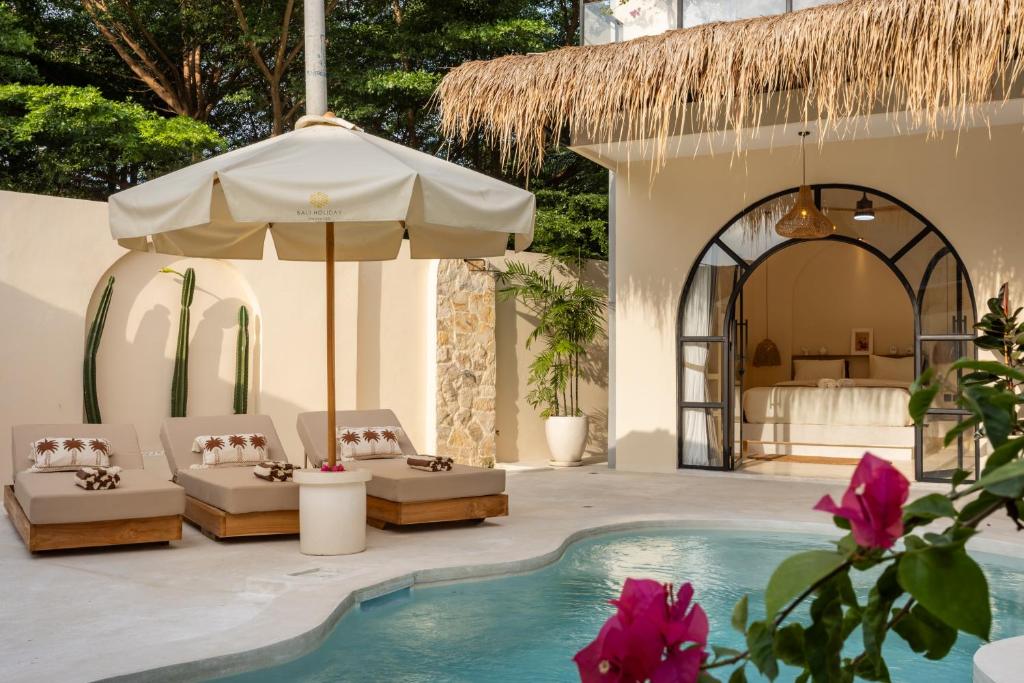 un patio con sedie, ombrellone e piscina di Sensorium VILLAS a Canggu