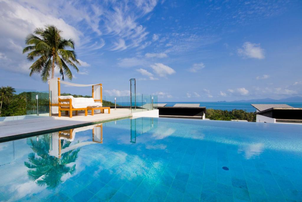 Una piscina con una palmera y el océano. en Code Samui Hotel, en Mae Nam