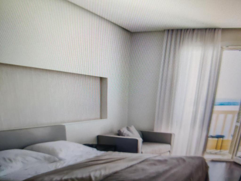 BahādrābādにあるHotel Ambikaのベッドと椅子と窓のある寝室