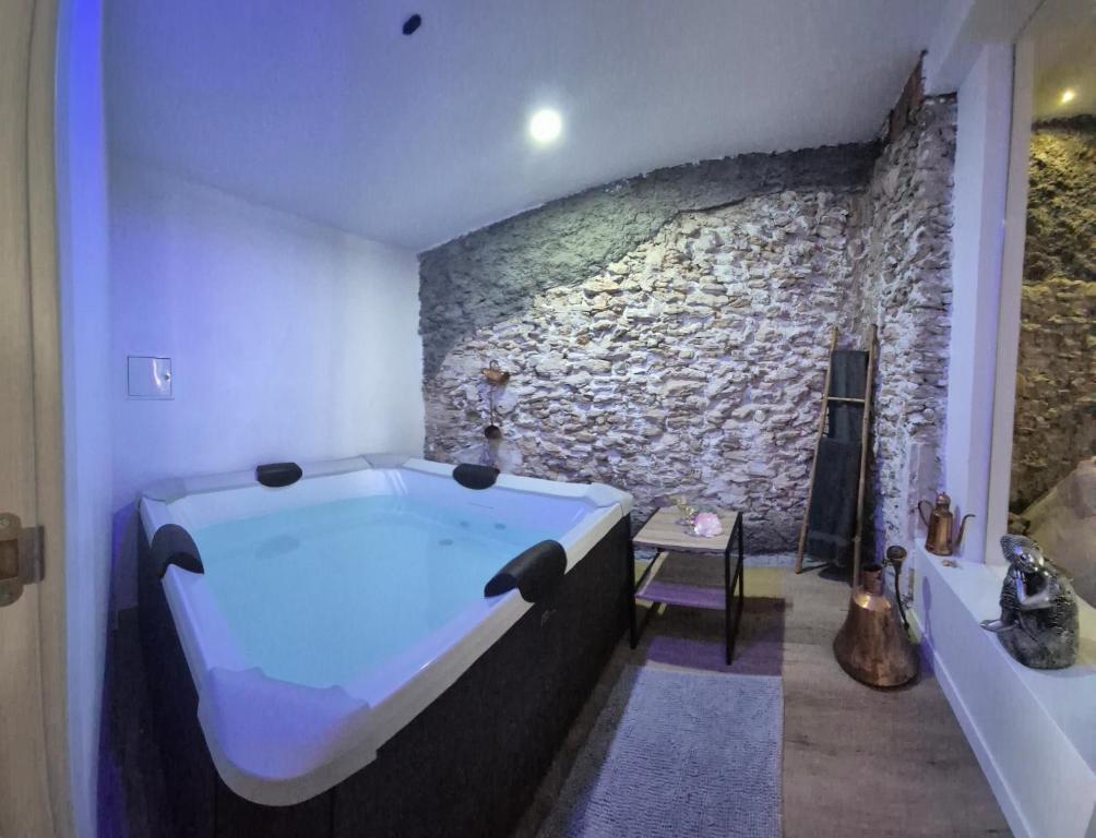 baño con bañera grande y pared de piedra. en fuga romantica, en Benisuera
