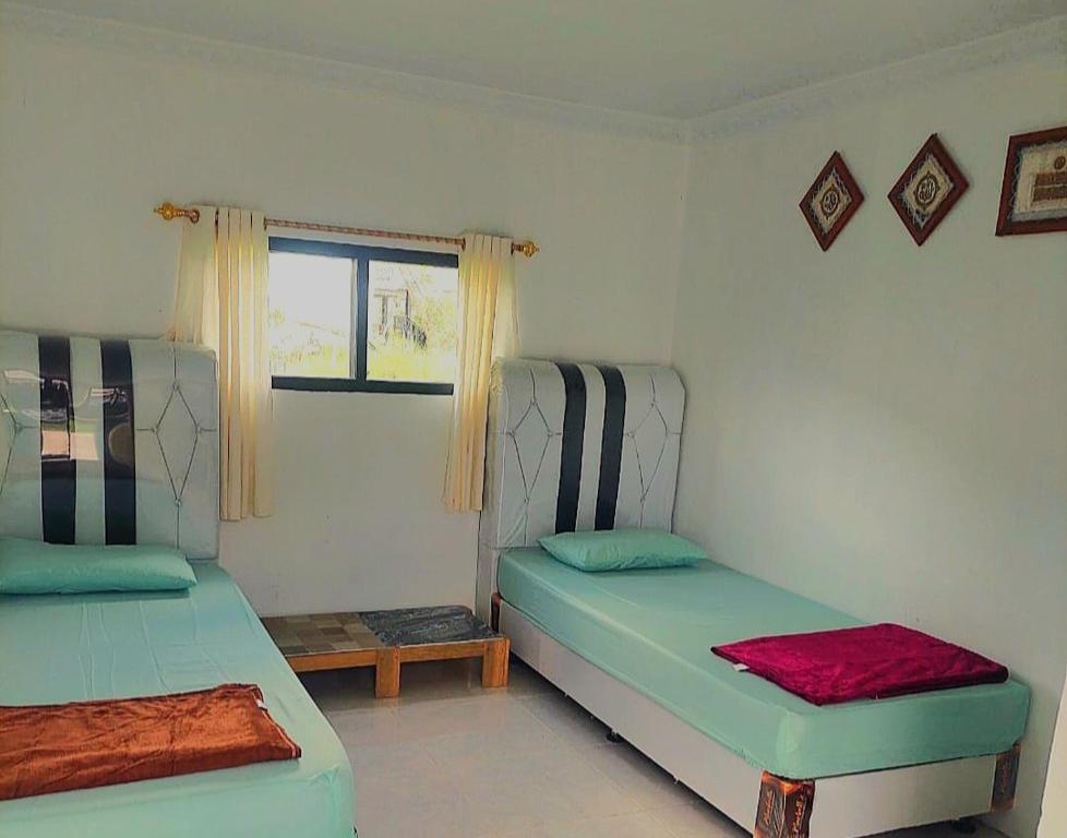 a room with two beds and a window at JANNAH Syariah in Takengon