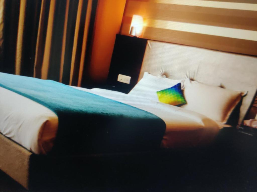 BahādrābādにあるHotel Shivのカラフルな枕付きのベッドが備わるホテルルームです。