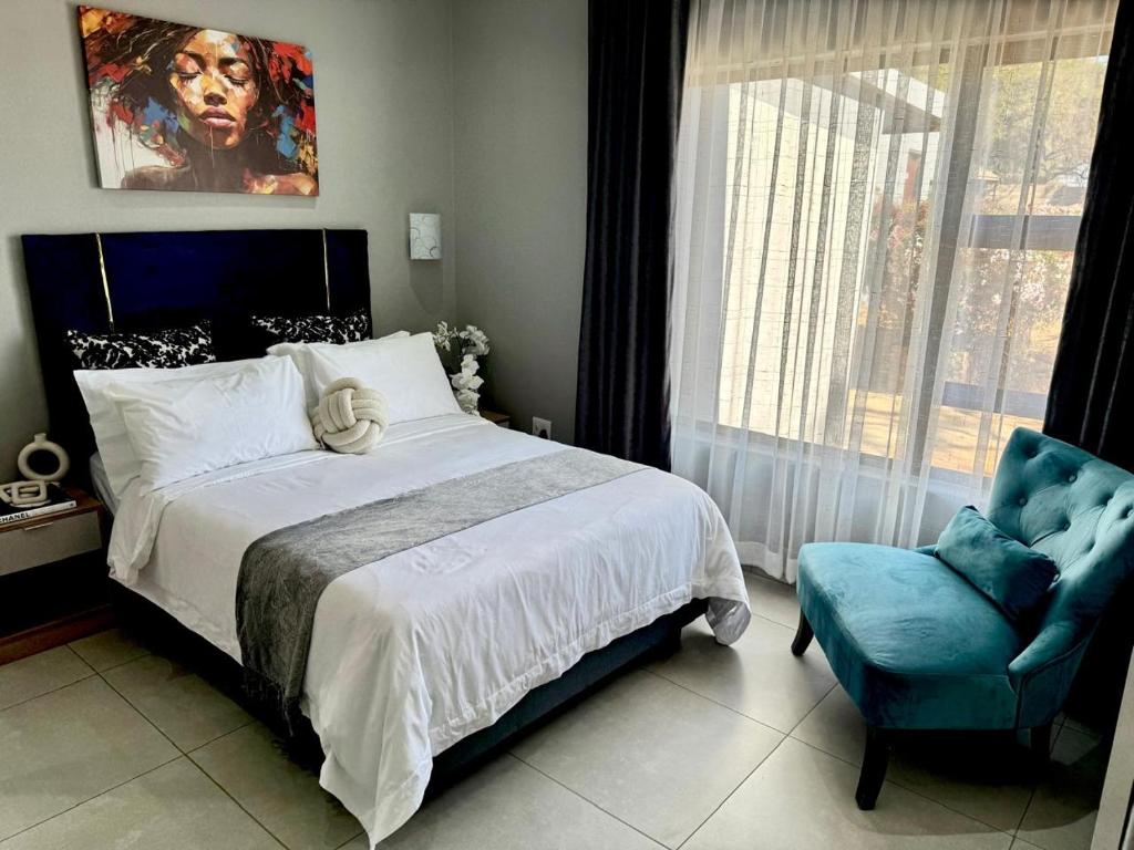 Un dormitorio con una cama grande y una silla azul. en GlowtiAirbnb, en Centurion