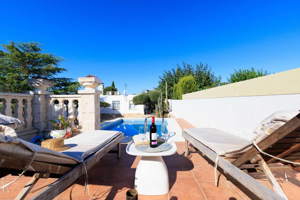 a patio with two chairs and a table with a bottle of wine at Mas Vilet by Unik Vacation in Catllar