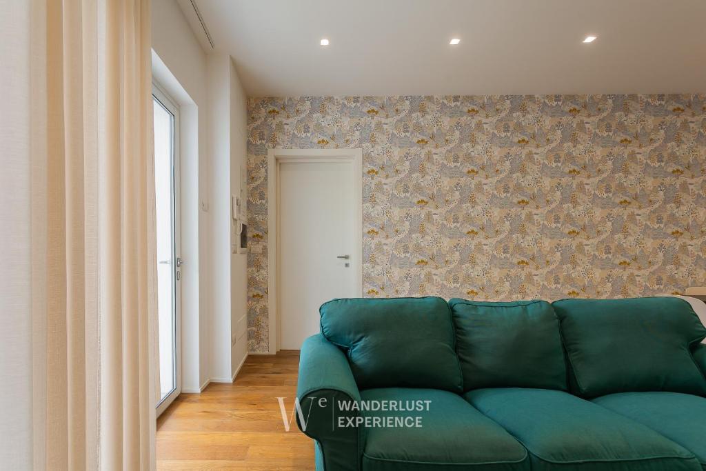 a living room with a green couch in front of a wall at Wanderlust Experience Maria Nicola in Conversano