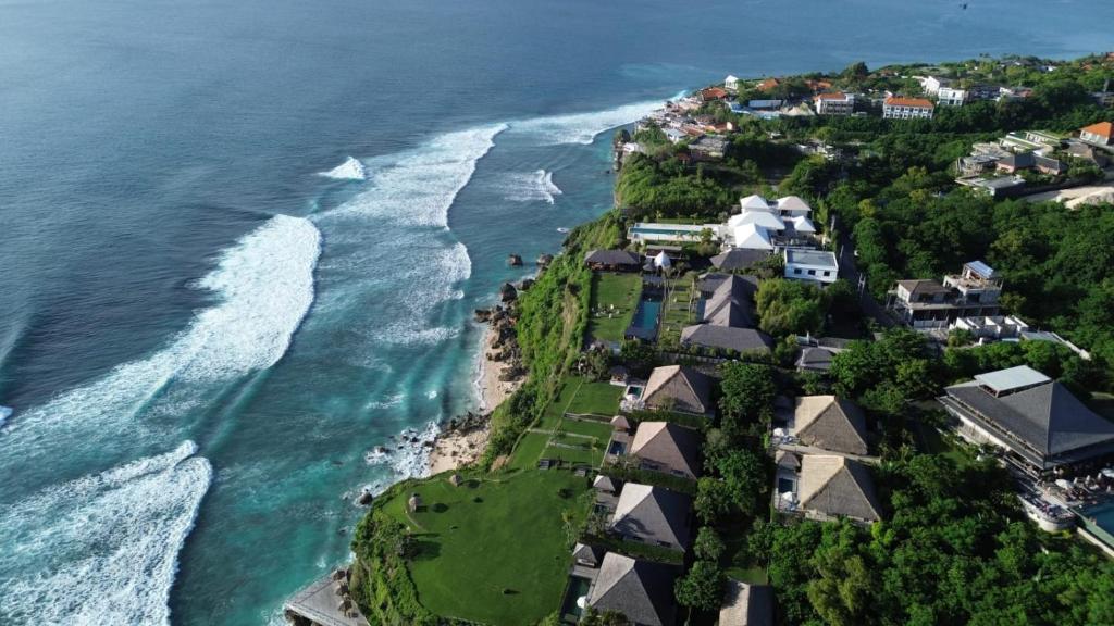 Luftaufnahme eines Strandes mit Häusern und dem Meer in der Unterkunft Serene Sunset Uluwatu in Uluwatu
