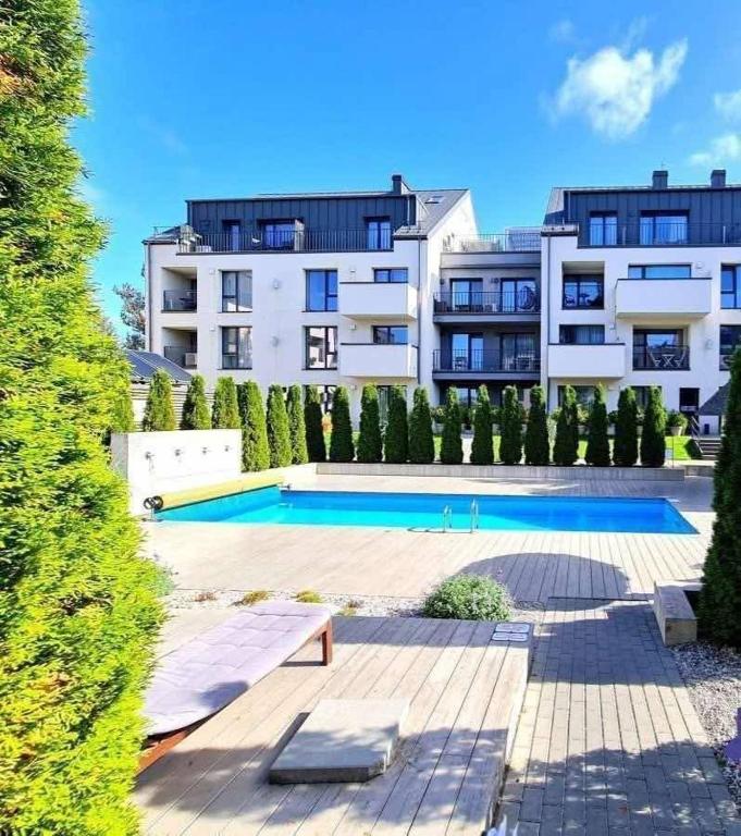 a large building with a swimming pool in front of a building at Apartamentai Gintaras in Palanga