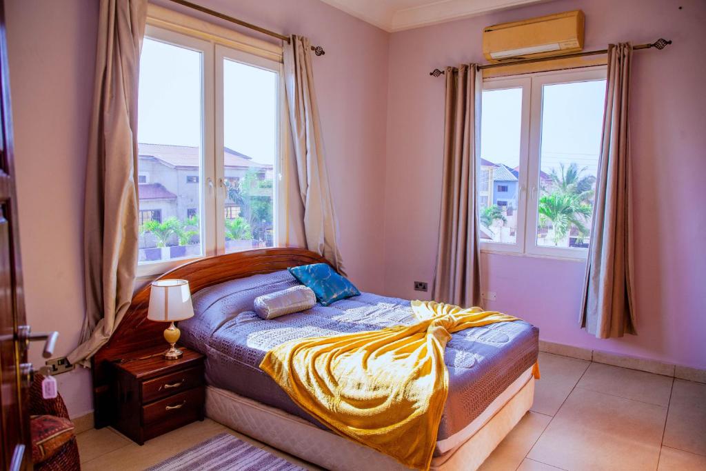 a bedroom with a bed and two windows at Villa Kidege in Accra