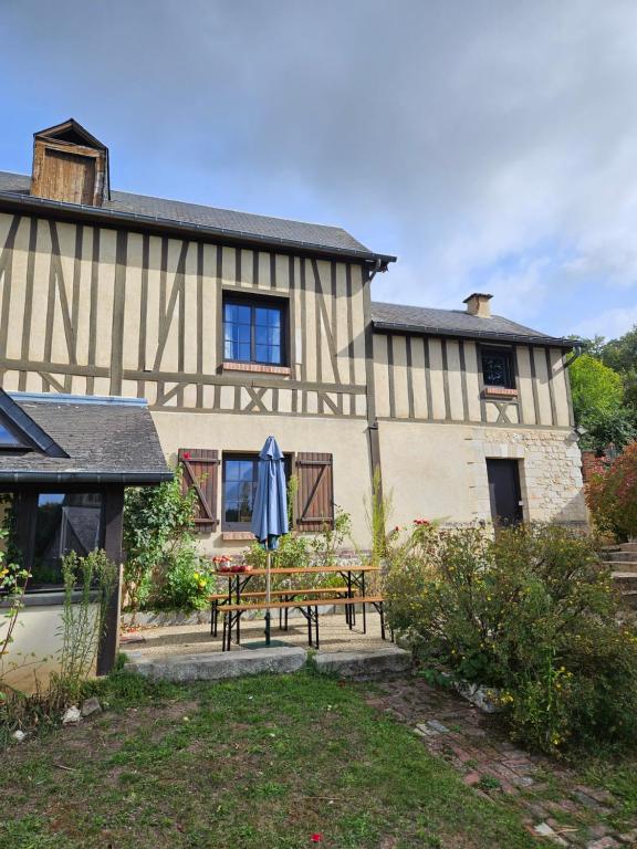 a house with a table and an umbrella in the yard at Maison normande au cœur de Le Bec-Hellouin in Le Bec-Hellouin