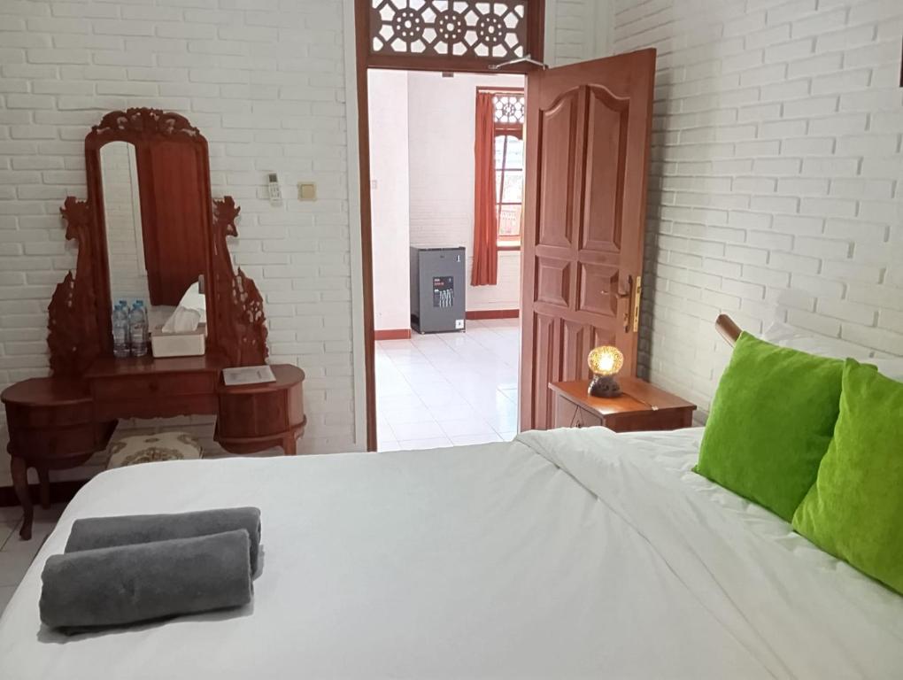 a bedroom with a white bed with a mirror and a door at dè Dayuh Guest House in Sanur