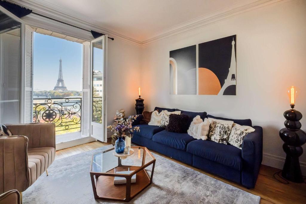 un salon avec un canapé bleu et une grande fenêtre dans l'établissement Luxury Flat Eiffel View 3BR 7 Guests, à Paris