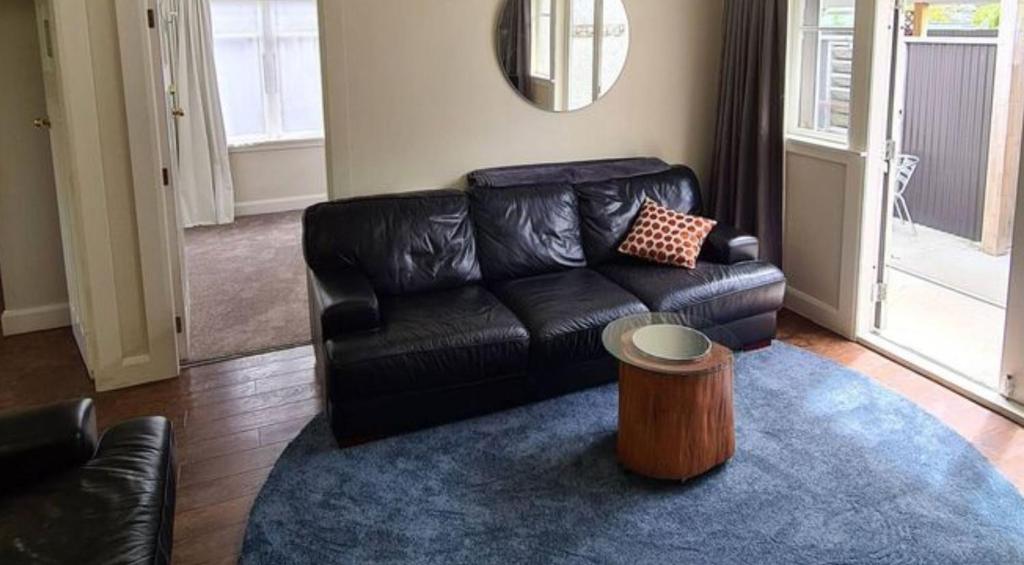a living room with a black leather couch and a table at Spacious 5 bedroom 2 bathroom Home Fast WIFi in Palmerston North