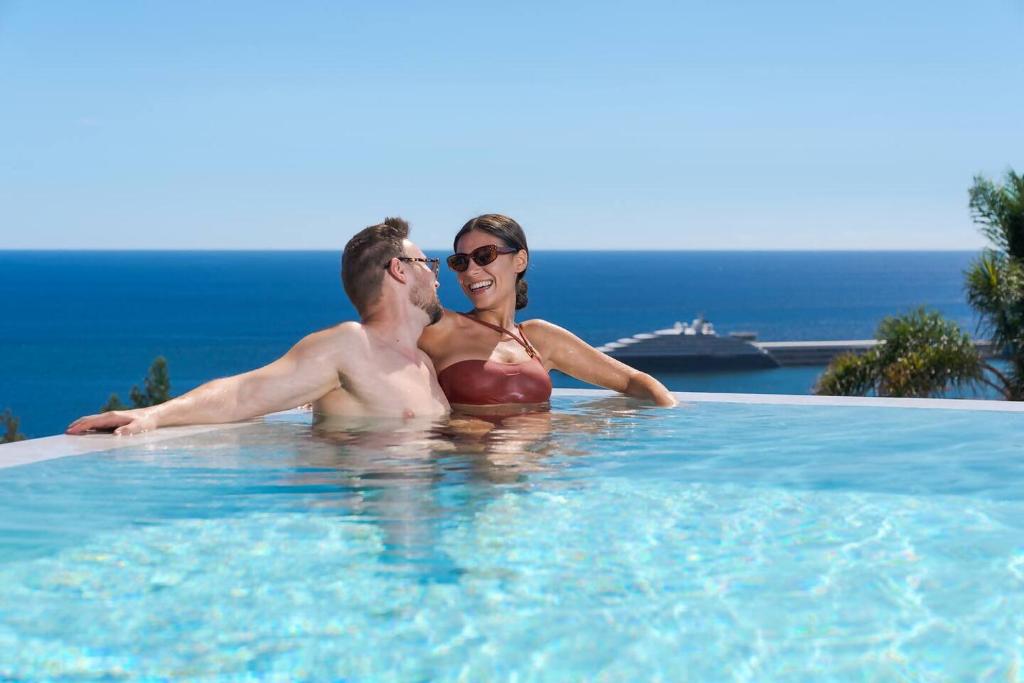 a man and a woman sitting in a swimming pool at Villa Mangoni - Brand New Luxury Villa in Funchal