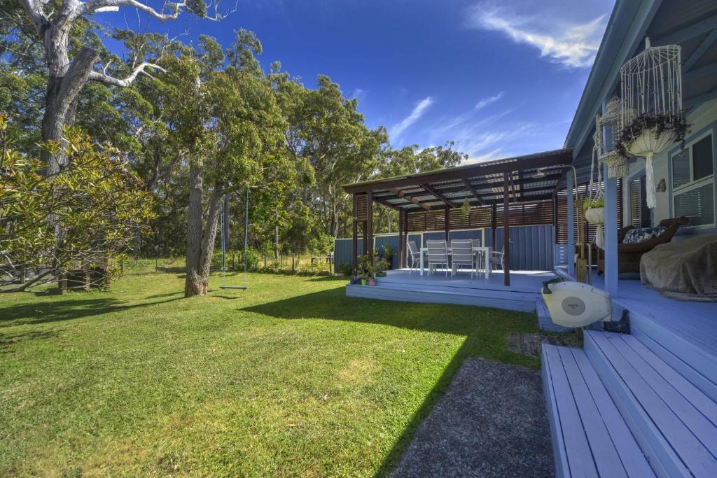 a backyard of a house with a wooden deck at Happy House - Pet Friendly - 5 Min Walk to Beach in Callala Beach