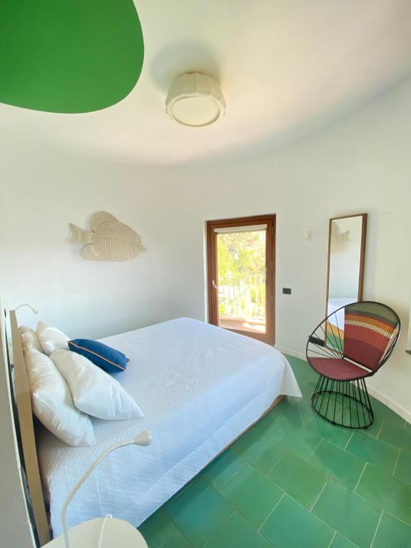 a white bedroom with a bed and a chair at Villa Alcado in Copanello