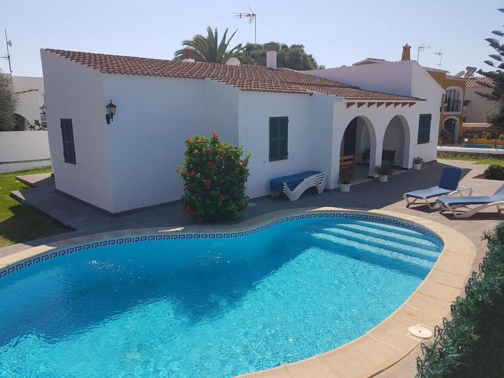 a villa with a swimming pool in front of a house at Villa Samba, luminosa y céntrica con piscina in Cala en Blanes