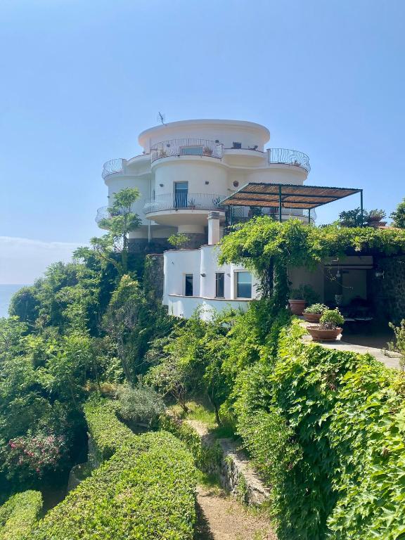 a building on top of a hill with bushes at Villa Alcado in Copanello