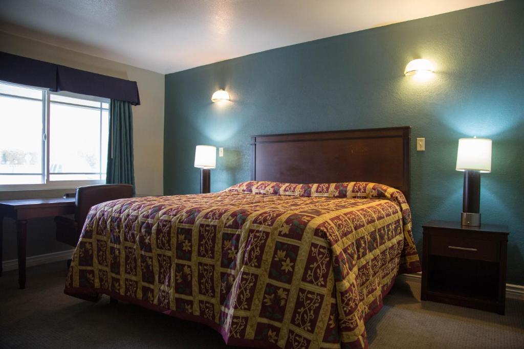 a bedroom with a bed and a desk and two lamps at Sahara Motel in Anaheim