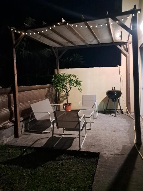a group of chairs under a pergola with lights at Au coin de la cheminée in Saint-Leu