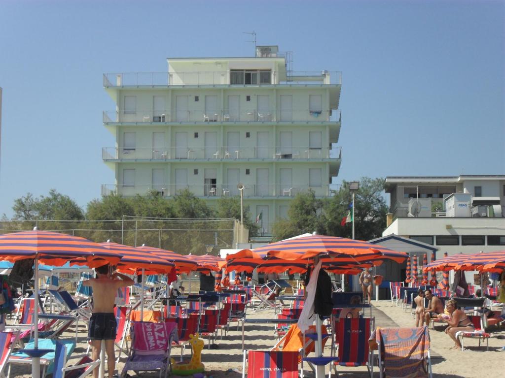 a beach with chairs and umbrellas and a building at Hotel Italia in Senigallia