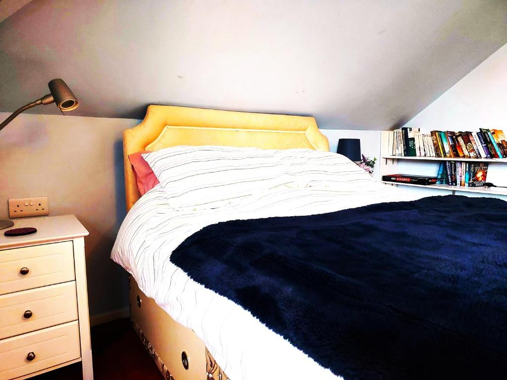 a bedroom with a bed with a yellow headboard and a book shelf at Double room with ensuite shower room in quiet, private house in Worthing