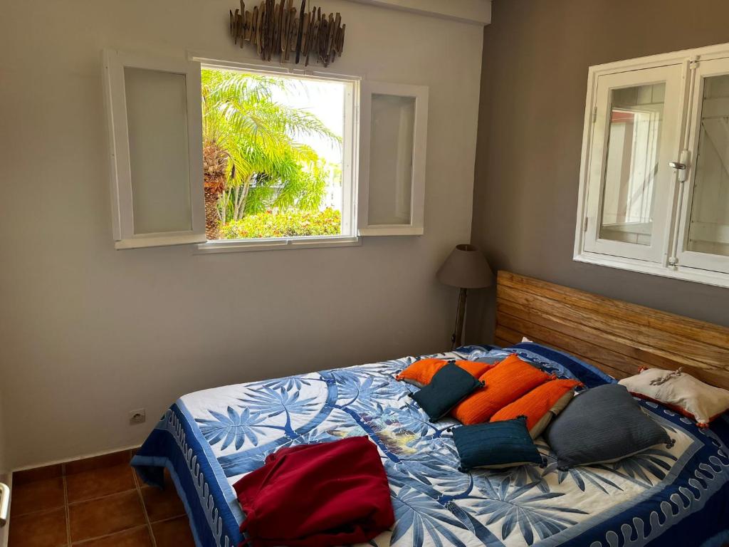 a bed in a bedroom with two windows at Villa malaurelia in Saint-François
